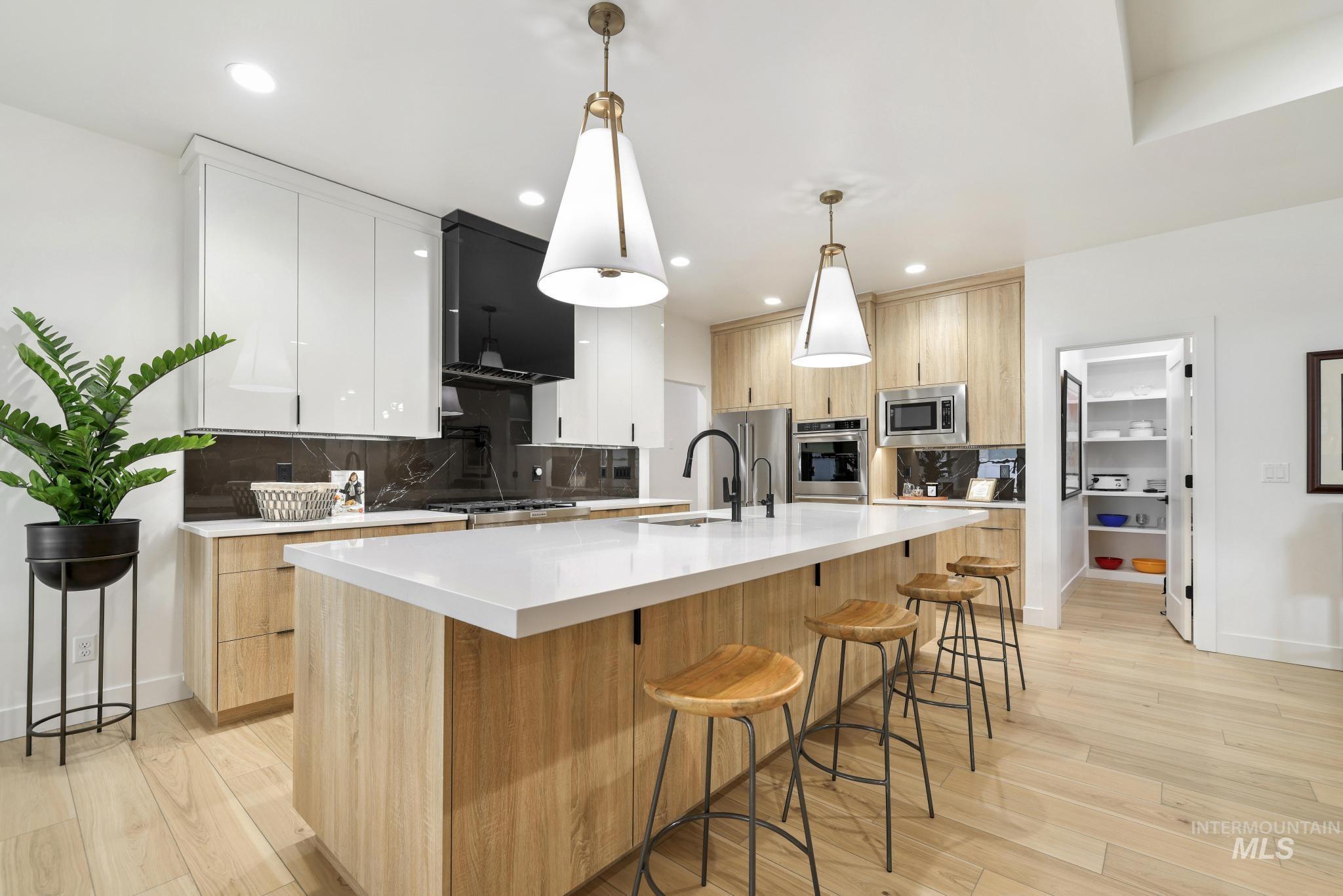 3140 Moonrise Road Twin Falls, ID 83301 - Photo 9 of 39 Dual tone kitchen featuring modern cabinets, two tone cabinetry, a breakfast bar, and light wood-style flooring