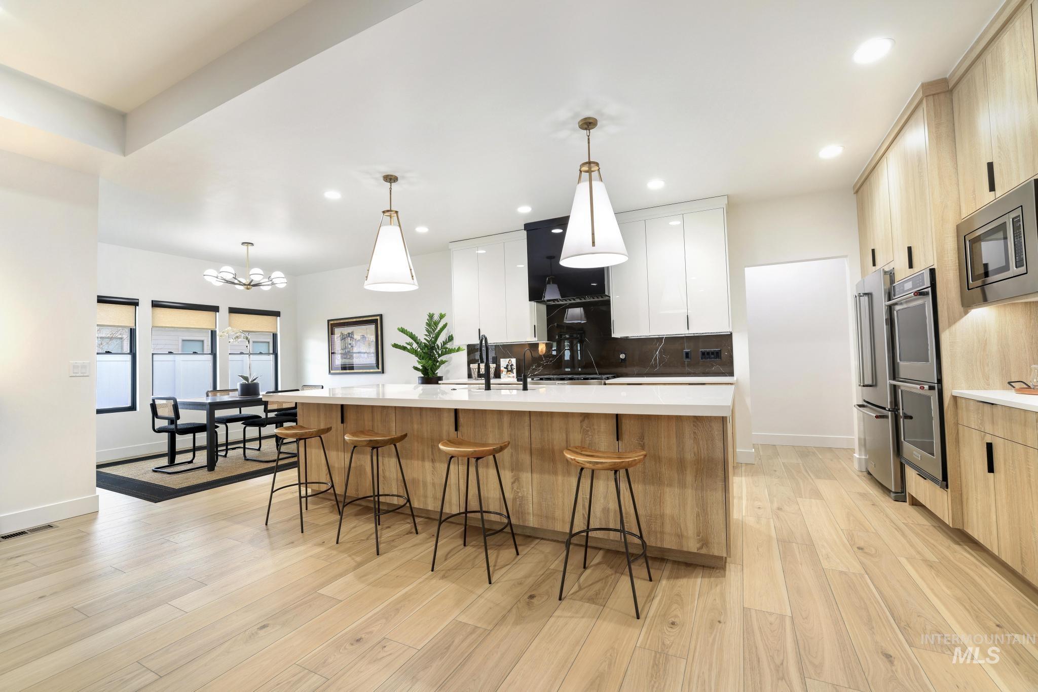 3140 Moonrise Road Twin Falls, ID 83301 - Photo 10 of 39 Dual tone kitchen with dual tone cabinets, a spacious island, a breakfast bar area, modern cabinets, and light wood finished floors