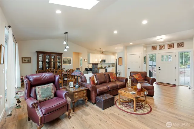 a living room with furniture kitchen view and a wooden floor