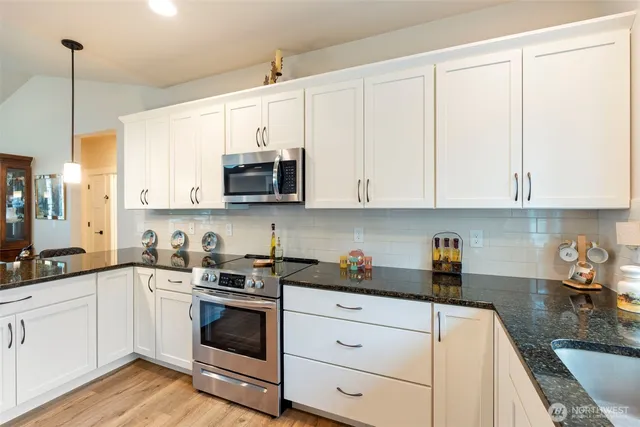 a kitchen with stainless steel appliances granite countertop white cabinets sink and stove
