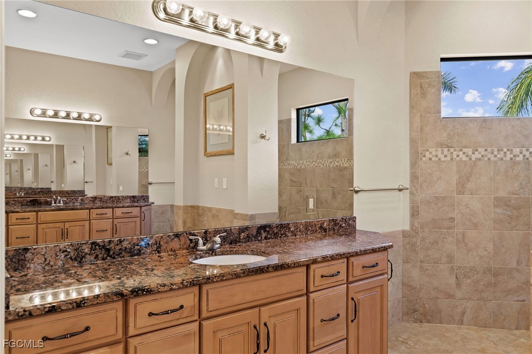 6057 Calusa Rdg Trail Bokeelia, FL 33922 - Photo 19 of 45 a bathroom with double vanity sinks a mirror and a shower