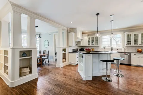 a kitchen with stainless steel appliances granite countertop wooden floors and white cabinets