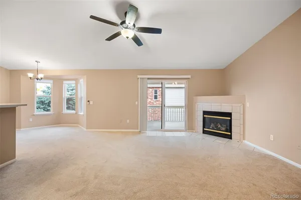 a view of a livingroom with a fireplace a ceiling fan and windows