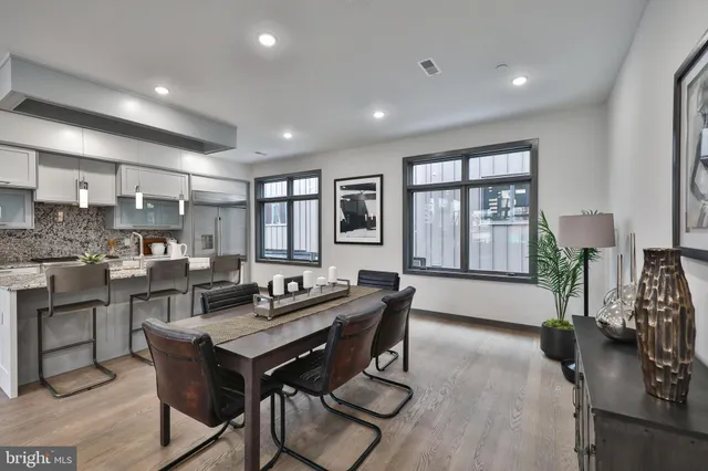 a kitchen with stainless steel appliances kitchen island granite countertop a dining table chairs stove and white cabinets