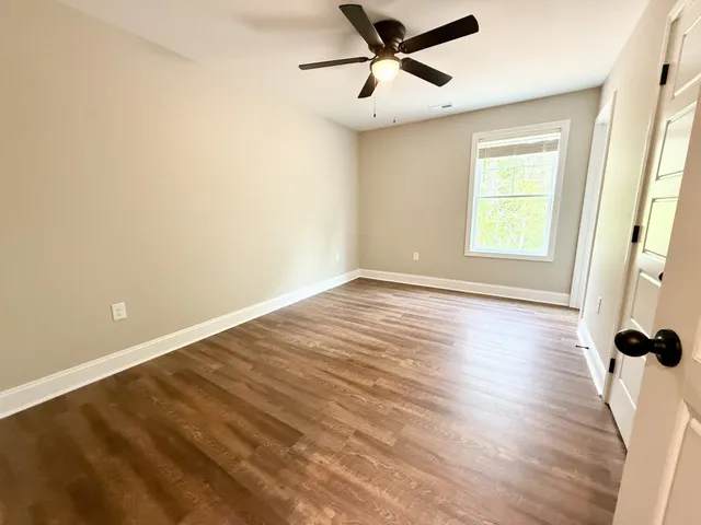 a view of a room with wooden floor and a ceiling fan