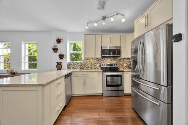 a kitchen with granite countertop a refrigerator stove and sink
