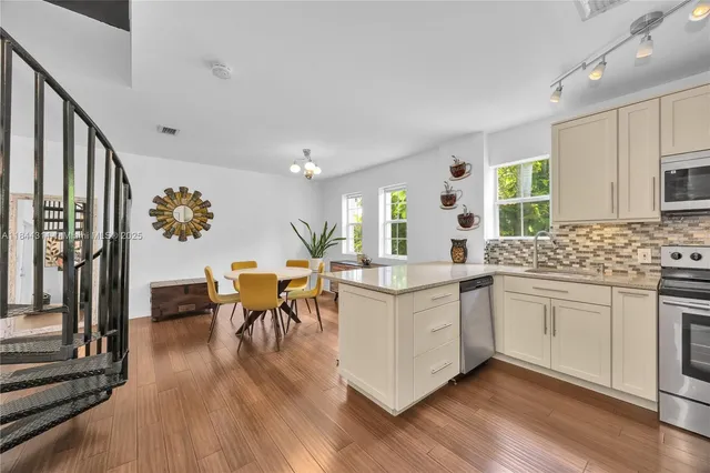 a kitchen with stainless steel appliances granite countertop hardwood floor sink stove dining table and chairs