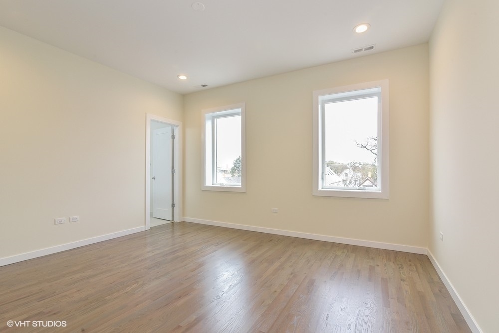 3326 West Irving Park Road, Unit 3E Chicago, IL 60618 - Photo 7 of 15 an empty room with wooden floor and window