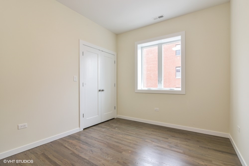 3326 West Irving Park Road, Unit 3E Chicago, IL 60618 - Photo 10 of 15 an empty room with wooden floor and windows