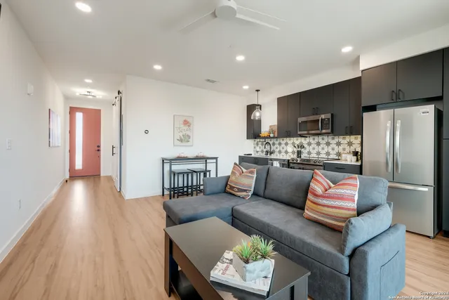 a living room with stainless steel appliances furniture and a wooden floor