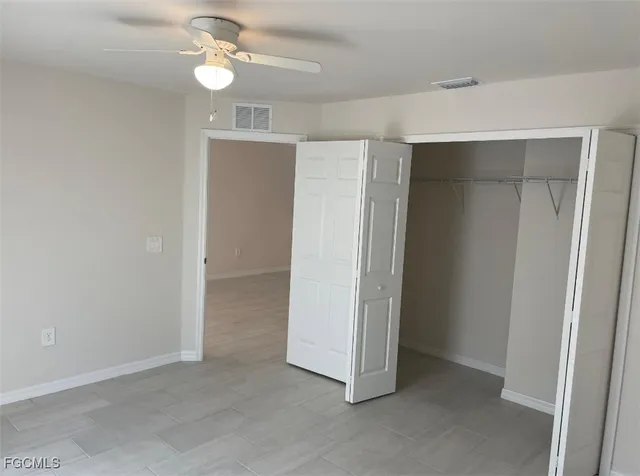 an empty room with closet and a ceiling fan