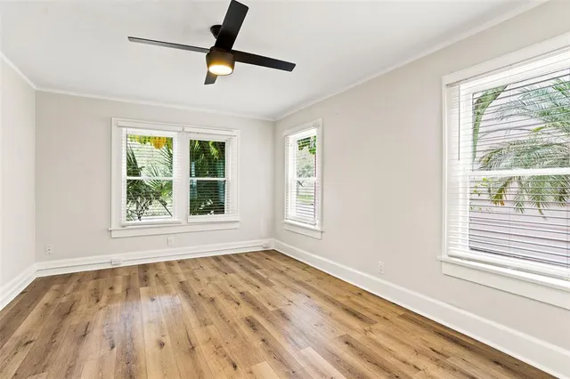 a view of empty room with wooden floor and fan