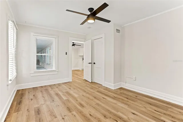 a view of empty room with wooden floor and fan