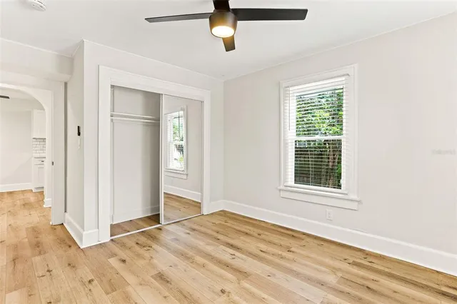 an empty room with wooden floor cabinet and windows