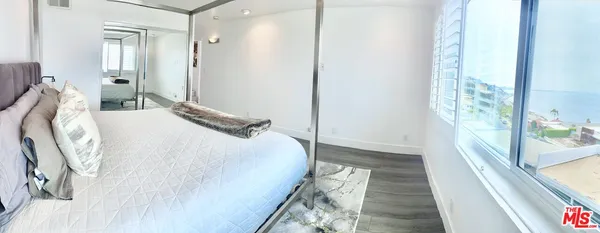 a bedroom with a bed and a large mirror next to a window