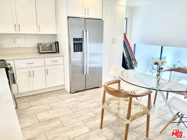 a kitchen with granite countertop a table chairs refrigerator and cabinets