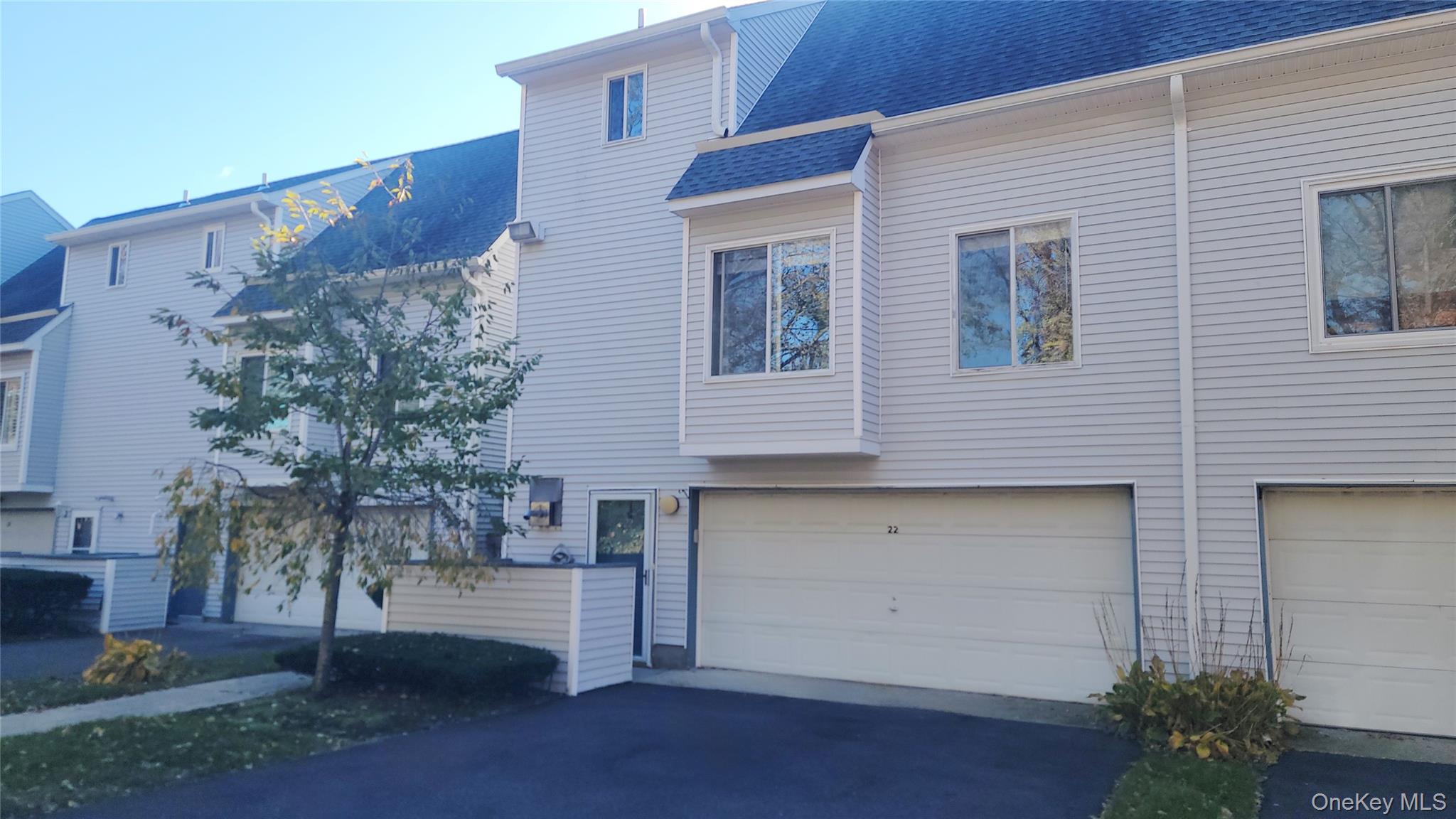 View of side of home with a shingled roof, a garage, and asphalt driveway