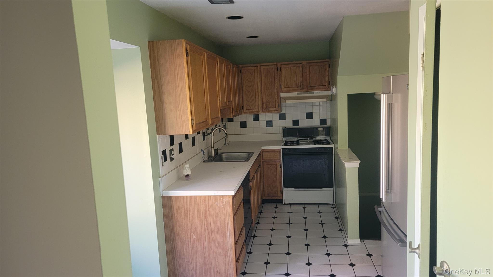 35 Gibbs Road, Unit 22 Coram, NY 11727 - Photo 6 of 20 Kitchen featuring light countertops, decorative backsplash, gas range oven, and brown cabinets
