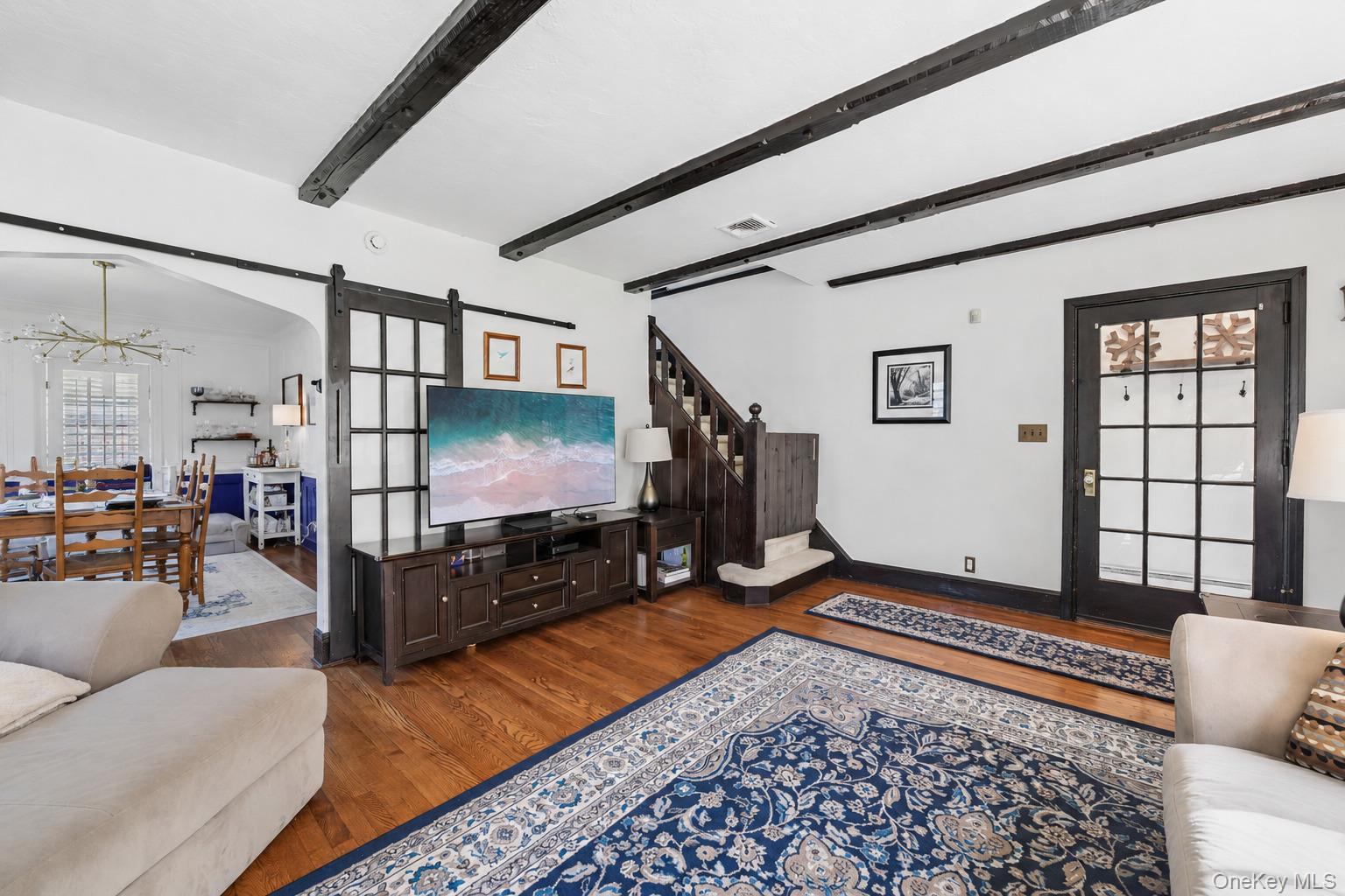 60 Croyden Road Mineola, NY 11501 - Photo 4 of 33 Living area featuring wood-finish flooring, exposed ceiling beams, and a staircase with wood newel posts