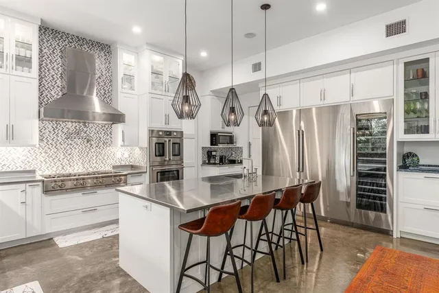 a kitchen with stainless steel appliances kitchen island granite countertop a table chairs and a refrigerator