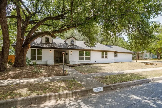 a view of a yard in front of a house with large tree