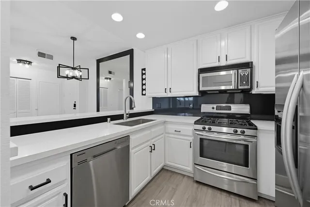 a kitchen with white cabinets stainless steel appliances and sink