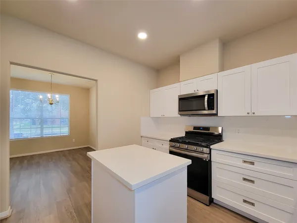 a kitchen with stainless steel appliances a stove a microwave and a hard wood floors