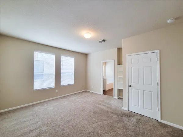 a view of an empty room with a window and a kitchen