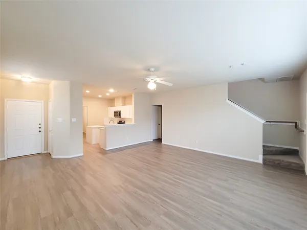 a view of a big room with wooden floor and a kitchen