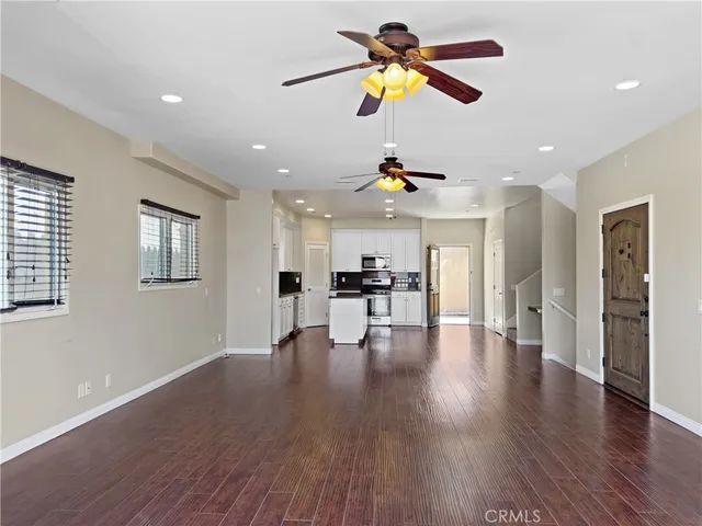 a view of an empty room with wooden floor and a ceiling fan