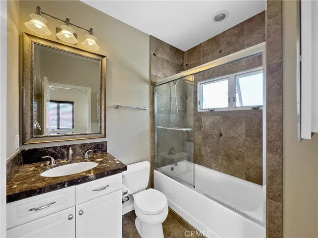 a bathroom with a bathtub shower sink vanity mirror and toilet