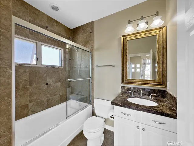 a bathroom with a granite countertop sink a toilet a mirror and bathtub