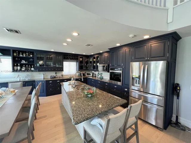 a large kitchen with granite countertop lots of counter space dining table and stainless steel appliances
