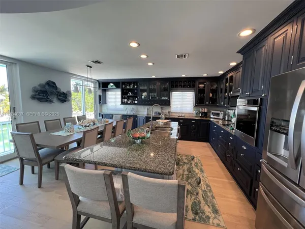a large kitchen with granite countertop lots of counter space dining table and stainless steel appliances