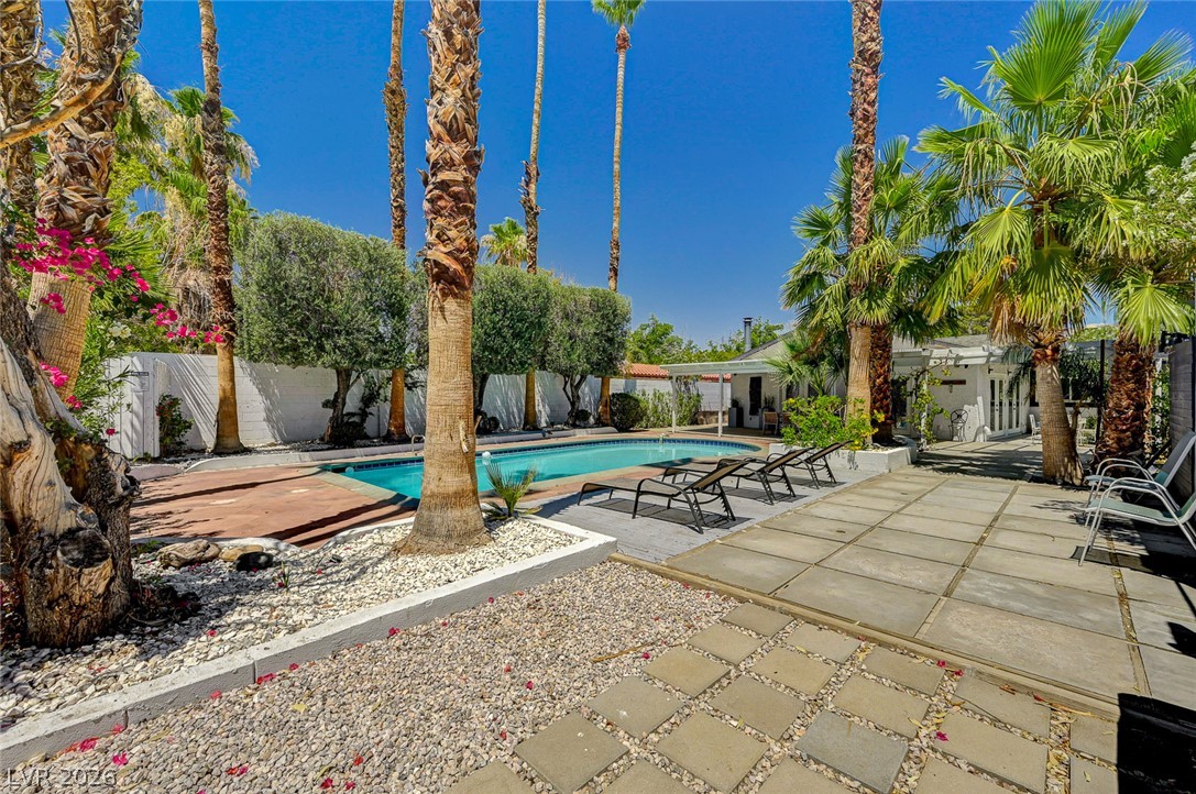 4153 Woodcrest Road Las Vegas, NV 89121 - Photo 50 of 58 A private pool oasis awaits, surrounded by mature palm trees and ample paved patio space for leisure.