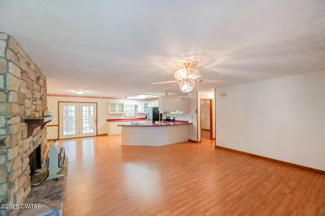 an empty room with wooden floor fireplace and windows
