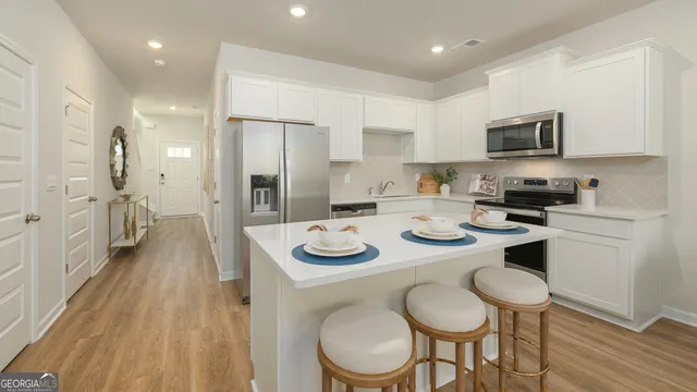 a kitchen with stainless steel appliances granite countertop a kitchen island a stove a table and chairs in it