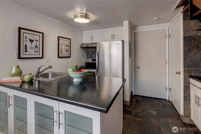 a kitchen with stainless steel appliances granite countertop a refrigerator a sink a stove and white cabinets