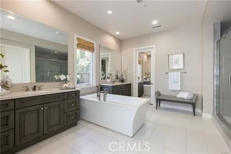 a spacious bathroom with a double vanity sink a large mirror and a bathtub