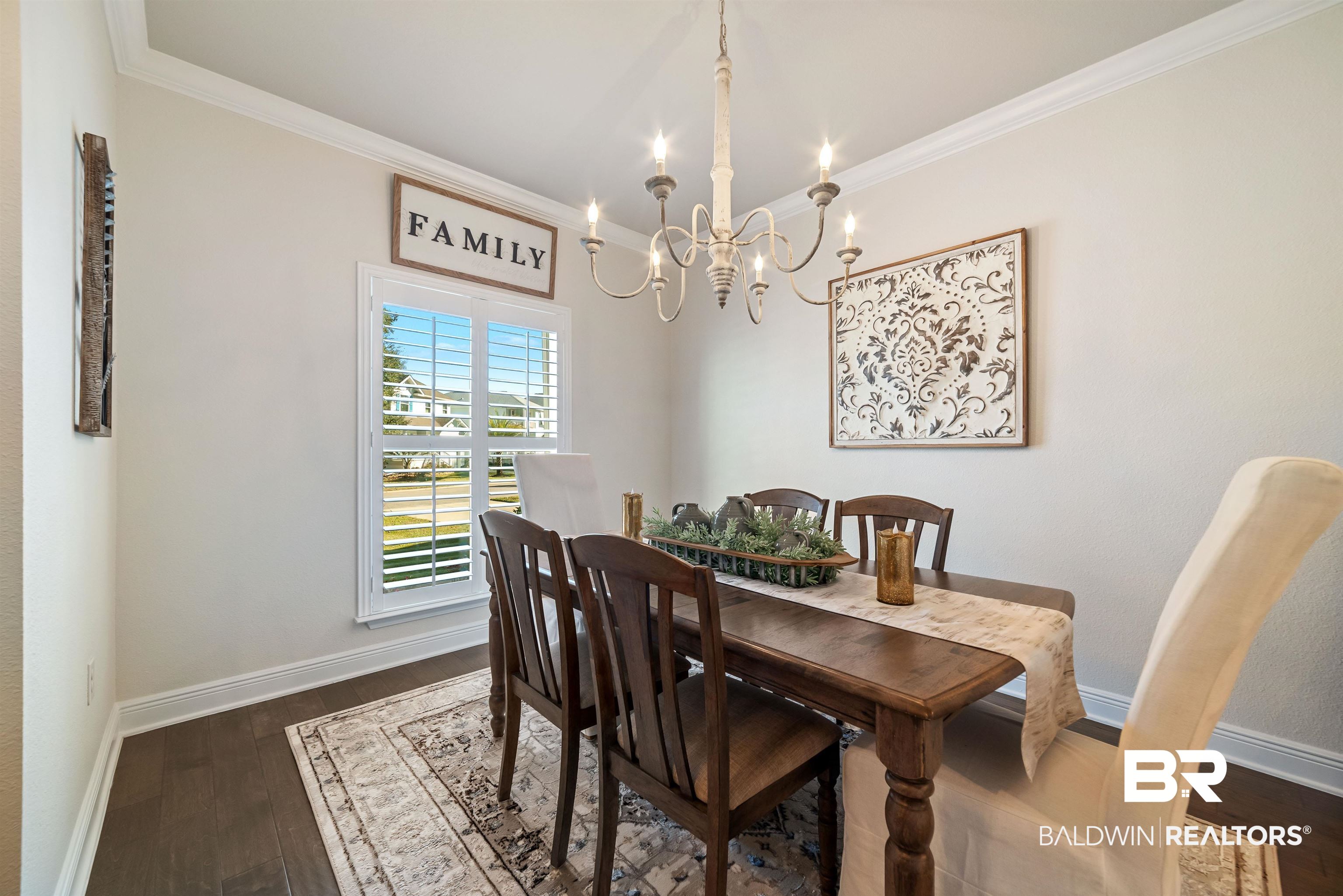 1290 Mako Loop Gulf Shores, AL 36542 - Photo 3 of 50 Dining area featuring dark wood-type flooring, ornamental molding, baseboards, and an inviting chandelier