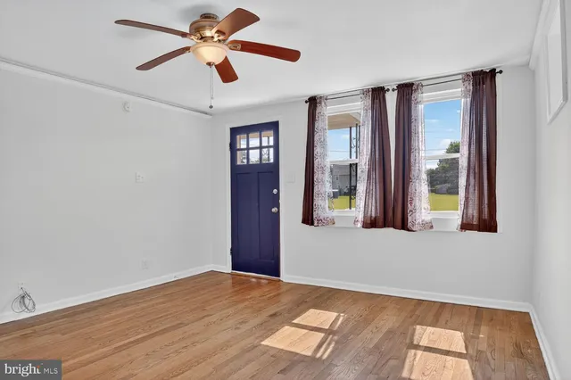 a view of an empty room with window and chandelier fan