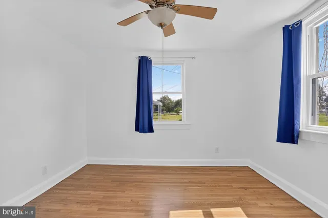 a view of an empty room with window and wooden floor