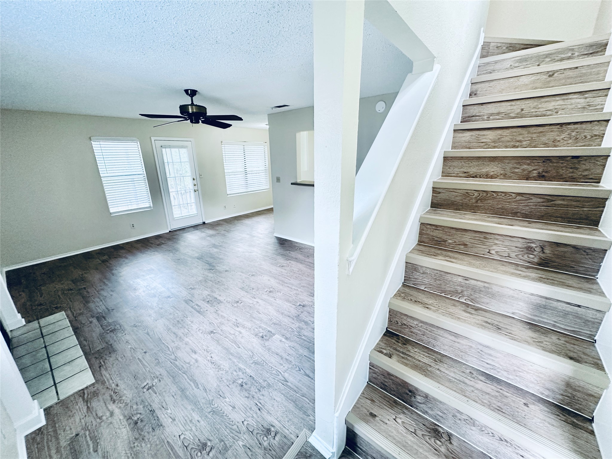 379 Fantail Loop, Unit B Austin, TX 78734 - Photo 3 of 33 Warm wood-look flooring anchors the open living space adjacent to a prominent staircase.