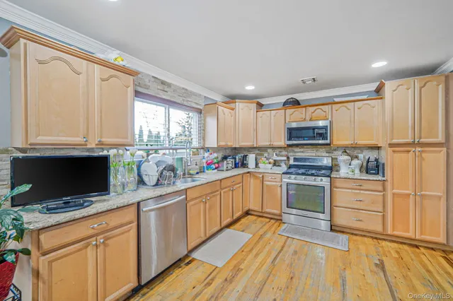 a kitchen with stainless steel appliances granite countertop a stove top oven a sink dishwasher and a refrigerator with wooden floor