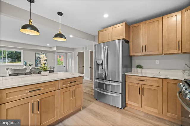 a kitchen with stainless steel appliances granite countertop a refrigerator a sink dishwasher a stove and white cabinets with wooden floor