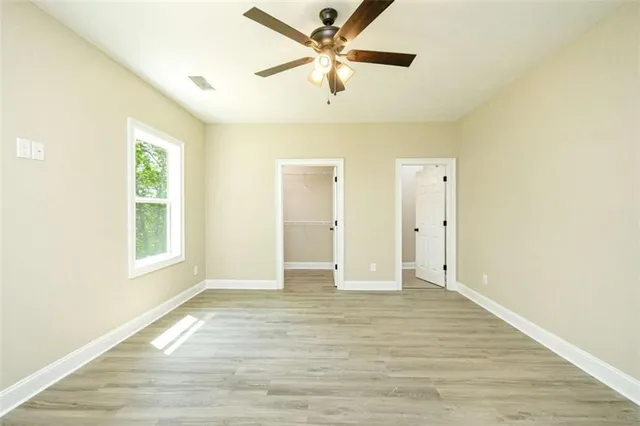a view of an empty room with window and a ceiling fan