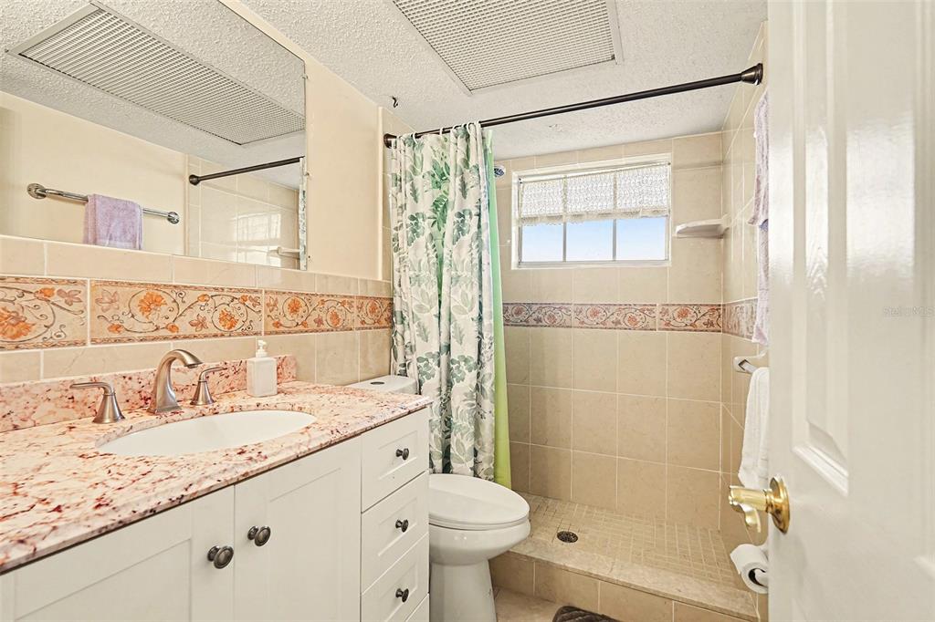 4742 Azalea Drive, Unit 103 New Port Richey, FL 34652 - Photo 20 of 33 a bathroom with a granite countertop sink toilet and shower