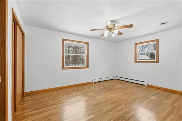 a view of empty room with wooden floor and fan
