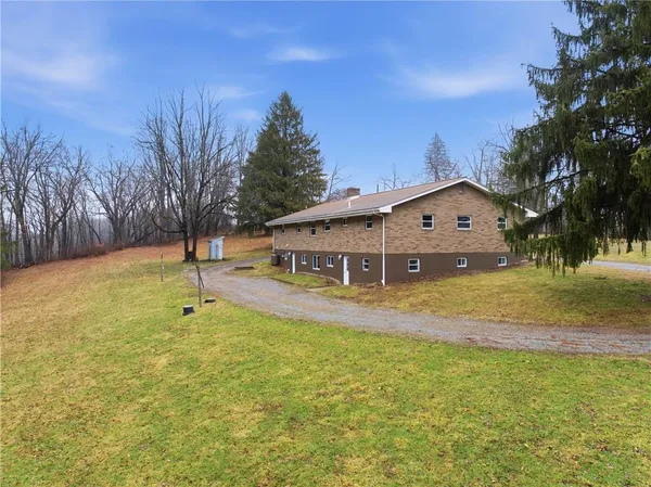 a view of a house with pool and trees in the background