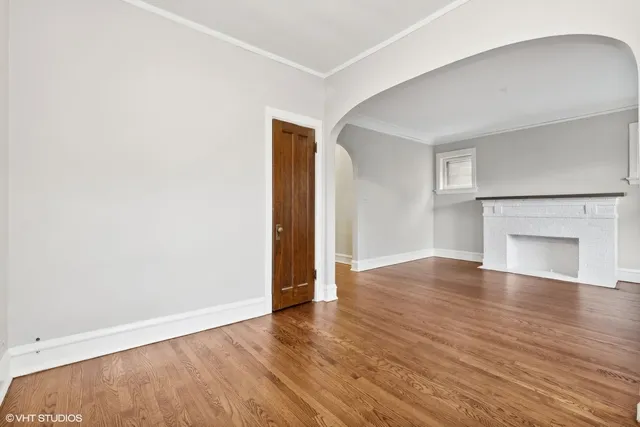 an empty room with wooden floor and fireplace
